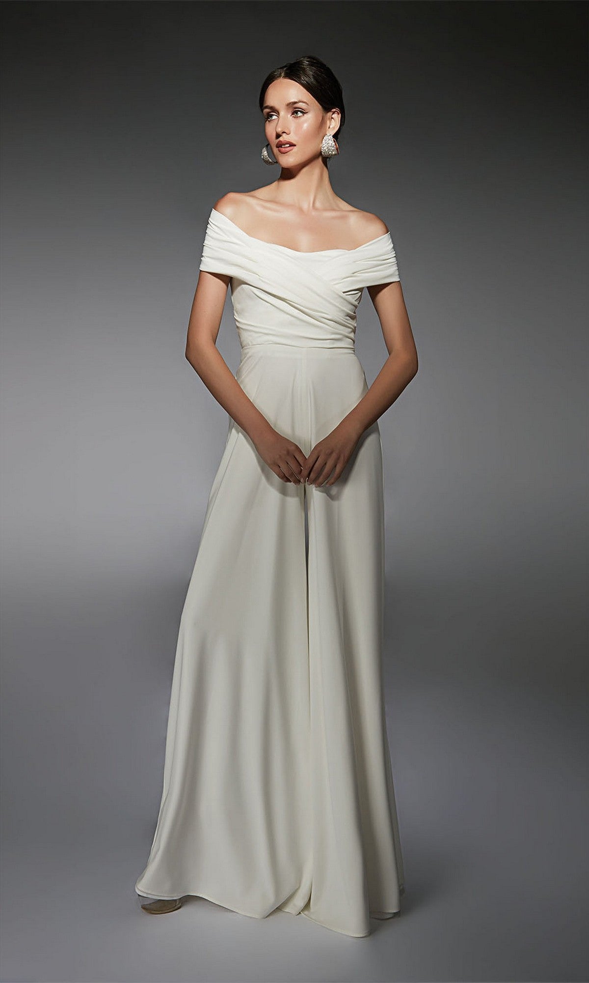 Woman wearing an Alyce 70067 ivory long formal dress, standing against a plain gray background.